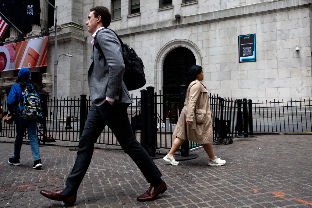 Workers and tourists pass the New York Stock Exchange on Wall Street.