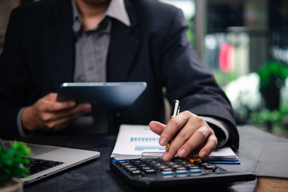 A business accountant reviews financial documents and uses a tablet and calculator to plan business strategies and data analysis.