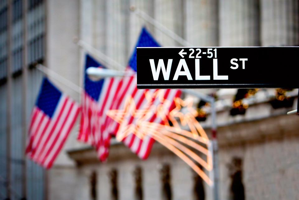 Wall Street sign with American flags in the background.